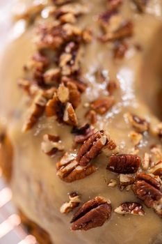 Frosting pumpkin bundt cake with a toffee glaze and garnish with toasted pecans.