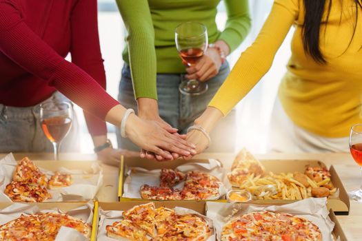 Friends at birthday party clinking glasses with champagne and pizza, enjoying christmas vacation, pizza on the table. Holiday Party event.