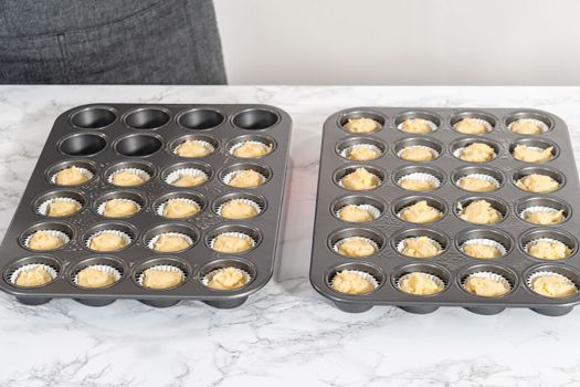 Scooping cupcake batter with dough scoop into a baking pan with liners to bake American flag mini cupcakes.