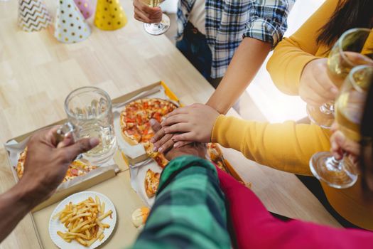 Friends at birthday party clinking glasses with champagne and pizza, enjoying Christmas vacation, pizza on the table. Holiday Party event