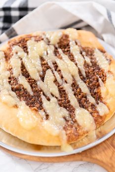 Freshly baked cinnamon dessert pizza with cream cheese drizzle.