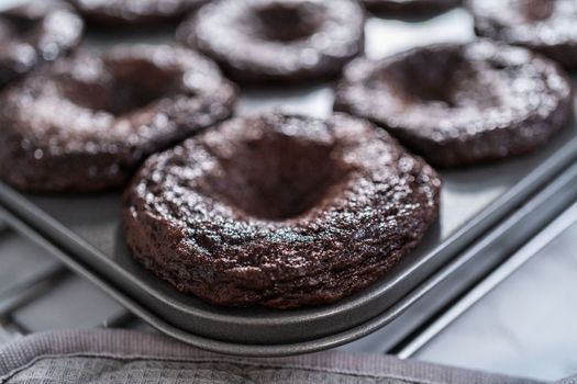 Cooling freshly baked chocolate cupcakes in a metal cupcake pan.