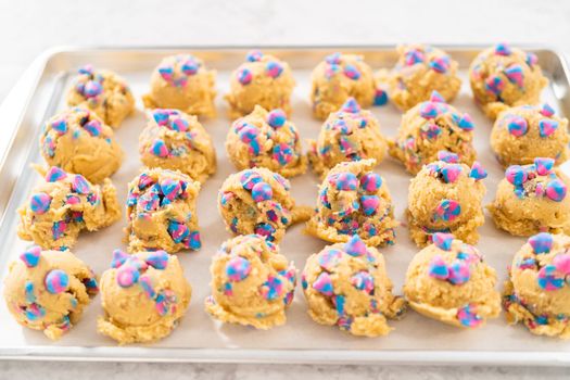 Chilled cookie dough scoops on the baking sheet to bake unicorn chocolate chip cookies.