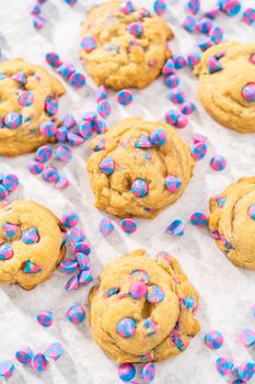Freshly baked unicorn chocolate chip cookies with rainbow chocolate chips on the counter.