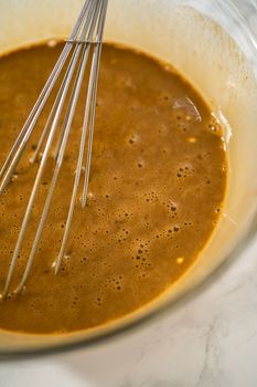 Mixing ingredients in a large glass mixing bowl to bake gingerbread cupcakes.