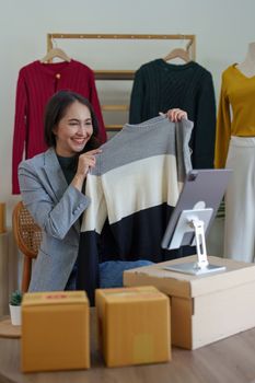 Asian Woman fashion designer cloth tailor creative working for new collection. Happy online store owner preparing an order for shipping.