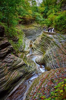 Image of Mossy and leaf covered layered rock gorge with river and overlook for tourists