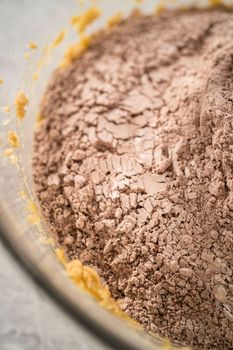 Mixing ingredients in a large glass mixing bowl with a kitchen mixer to bake chocolate cookies with peppermint chips.