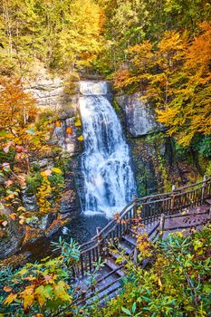 Image of Stunning boardwalk along huge raging waterfall over cliffs surrounded by fall foliage