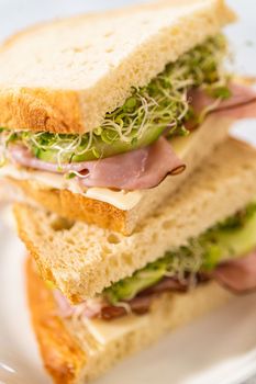 Stack of ham, cucumber, and sprout sandwiches on the white plate