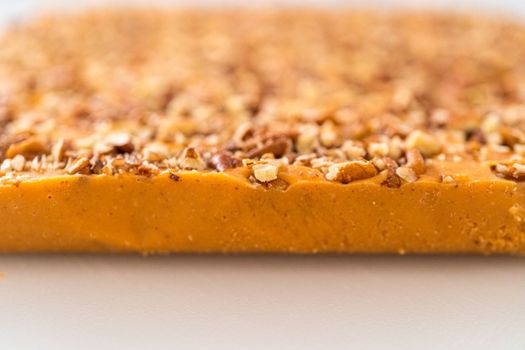 Scoring pumpkin spice fudge using a wheel dough cutter for cutting into small pieces.