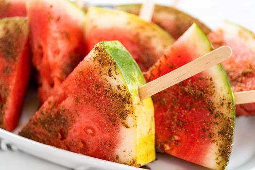 Chili lime watermelon pops on a white serving plate.