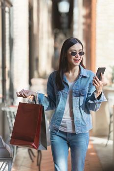 Asian fashionable woman walking at shopping mall with shopping bags while flash sale promotion.