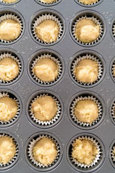 Scooping cupcake batter with dough scoop into a baking pan with liners to bake American flag mini cupcakes.