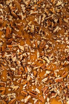 Pouring fudge mixture into the square glass baking pan lined with parchment paper to prepare pumpkin spice fudge.