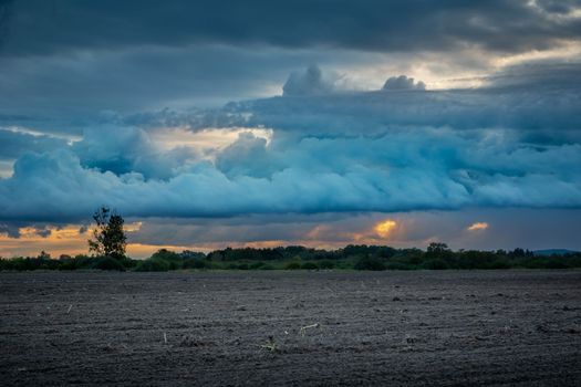 Blue evening cloudy sky over a plowed field, September view in the eastern Poland