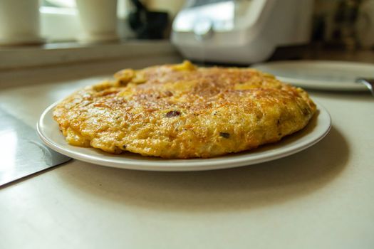 Single traditional Spanish tortilla on a plate, prepared at home