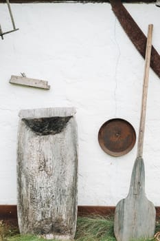 An old wooden wall of a house in the village and tools near the wall.