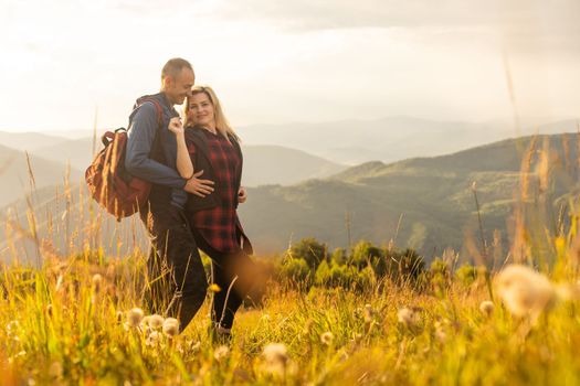 Happy traveler young couple resting in the mountains at sunset in spring or summer season