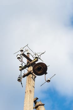 One old concrete street pole with a rusty iron part at the top and cut wires, Installation or dismantling of the power grid. A broken energy pillar.