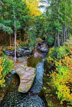 Image of Overlooking beautiful Vermont river with rocks carved by water in fall forest