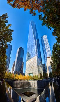 Image of New York City America 9 11 Ground Zero memorial fountain and One World Observatory surrounded by fall trees