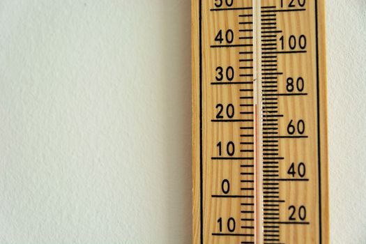 A wooden thermometer hanging on the wall, showing a temperature of 22 degrees Celsius