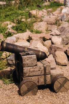 Medieval artillery piece on a wooden carriage standing outside in sunny weather.