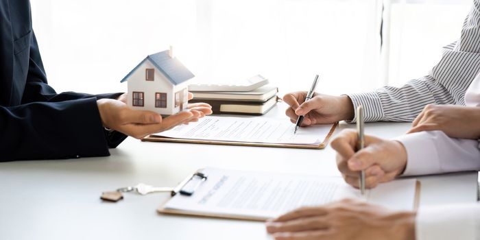 Real estate agent with couple closing a deal and signing a contract