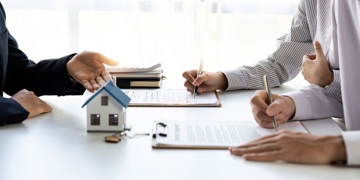 Real estate agent with couple closing a deal and signing a contract