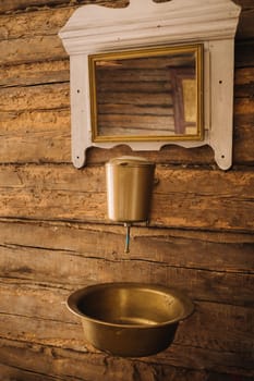Vintage shot of an old metal washbasin and mirror in a wooden house in the village.