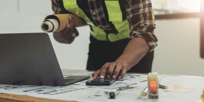 Close up of civil male engineer asian working on blueprint architectural project at construction site at desk in office