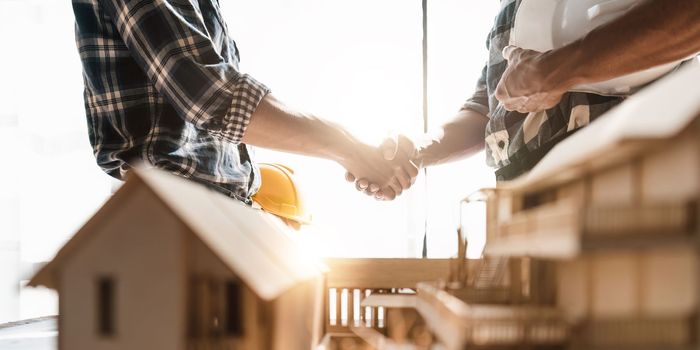 Architect and engineer construction workers shaking hands while working for teamwork and cooperation concept after finish an agreement in the office construction site, success collaboration concept.