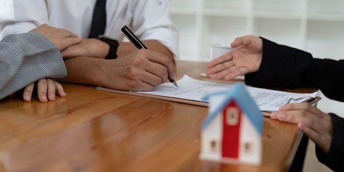 Young couple signing contract agreement with real estate agent