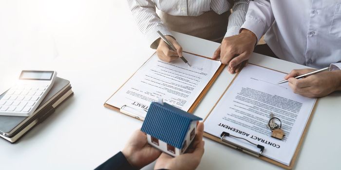 Real estate agent with couple closing a deal and signing a contract