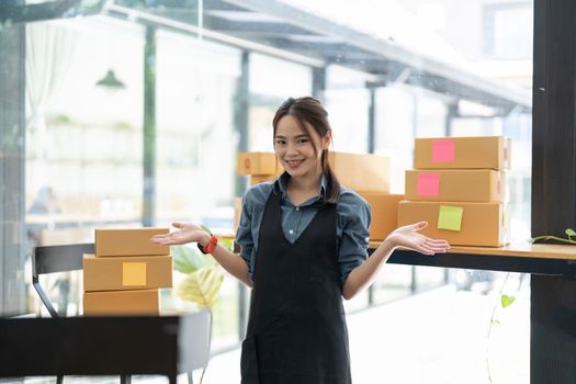 SME entrepreneur Small business entrepreneurs Online selling ideas, Happy Young Asian business owner work on computer and a boxes at home, delivery SME procurement package box deliver to customers.