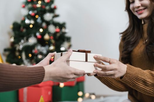 Exchange of gifts. Woman gives to his woman surprise a gift box with red ribbon. Young loving couple celebrating Christmas Day. Romantic day. Winter holidays