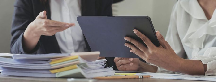 Close-up of hands using digital tablet, Two business colleague meeting to discussing the new project business strategy plan on wooden table in office. Briefing, brainstorming, consulting..