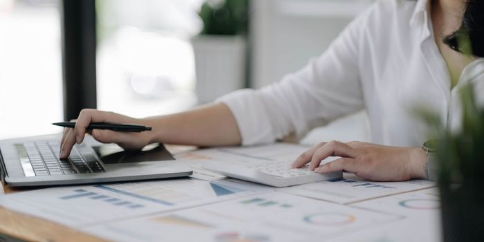 Business woman using calculator for do math finance on wooden desk in office and business working background, tax, accounting, statistics and analytic research concept.