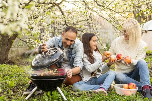 Happy family having a barbecue in their garden in spring. Leisure, food, family and holidays concept