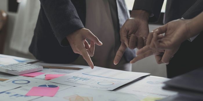 Close up photo of business working group of people are discussing together pointing at financial report, top or above view.