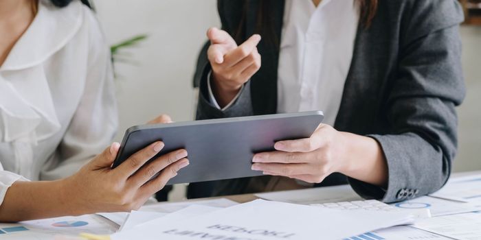 Close-up of hands using digital tablet, Two business colleague meeting to discussing the new project business strategy plan on wooden table in office. Briefing, brainstorming, consulting..