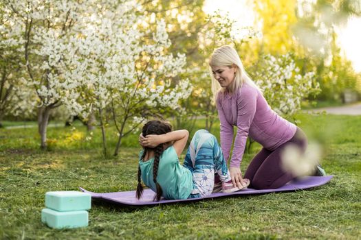 Mother and her daughter outdoors doing yoga, healthy lifestyle