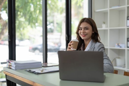 Charming young business woman with a smile working on laptop computer at office.