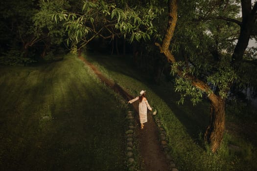 Portrait of a beautiful woman in a white dress and a hat with lilies of the valley. A girl in nature. Spring flowers.