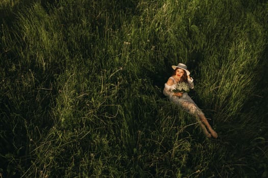 Portrait of a beautiful woman in a white dress and a hat with lilies of the valley. A girl in nature. Spring flowers.