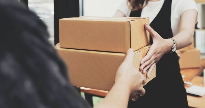 Closeup female hand accepting a delivery of boxes from deliverywoman..