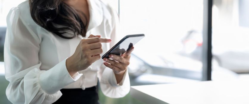 Close up young businesswoman using mobile phone in modern office