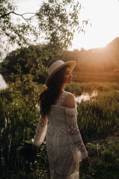 Portrait of a beautiful woman in a white dress and a hat with lilies of the valley. A girl in nature. Spring flowers.