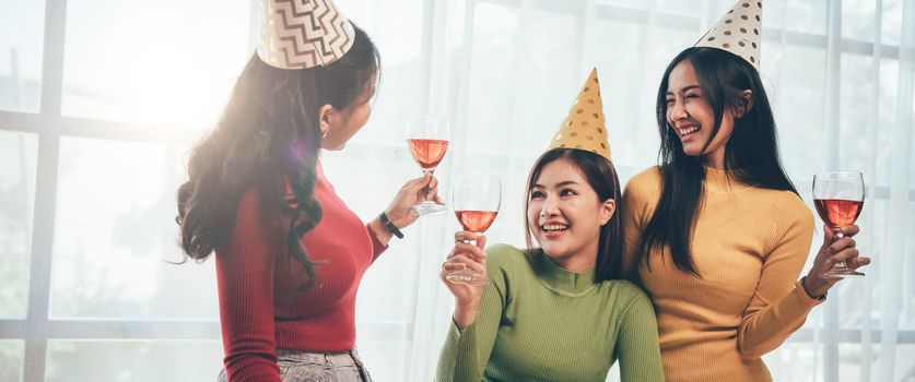 Group of Asian friends gather to celebrate Christmas with champagne and eating pizza at home. Joy of holiday party with friends or colleague concept.